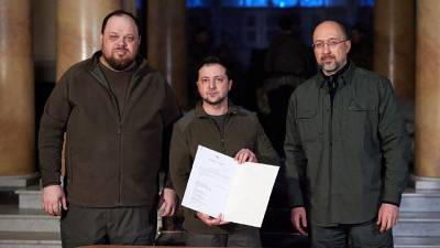 El presidente ucraniano Volodymyr Zelensky junto al primer ministro Denys Shmyhal y el jefe del Parlamento Ruslan Stefanchuk durante la firma de la solicitud para unirse a la UE.