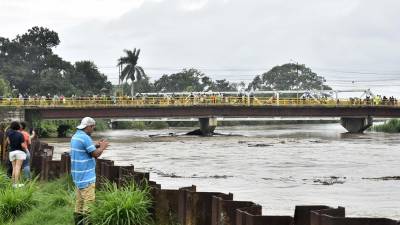 Pobladores observan el aumento del caudal del rio Chamelecón luego de que el gobierna emitiera alerta roja y ordenara evacuar las zonas bajas de la costa norte de Honduras debido al aumento de las lluvias por causa del huracán Julia, hoy en La Lima (Honduras). EFE/José Valle