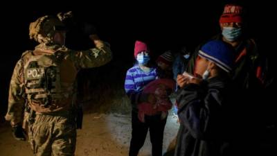 Un agente de la patrulla fronteriza se para ante un grupo de inmigrantes centroamericanos que llegan ilegalmente de México. AFP