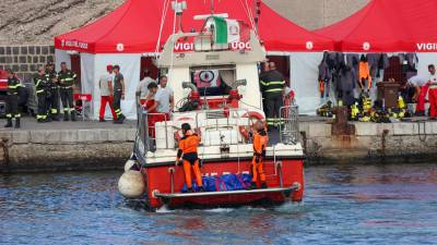 El personal de rescate llega con otro cuerpo de un pasajero del yate Bayesian después de la recuperación por buzos de bomberos, en el puerto de Porticello, cerca de Palermo.