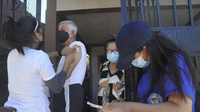 El personal de Salud aplica una vacuna contra la influenza a un adulto mayor.