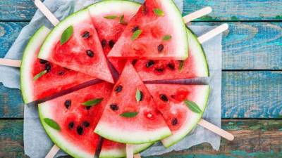 Slices of fresh juicy watermelon on a paper closeup on rustic wooden table