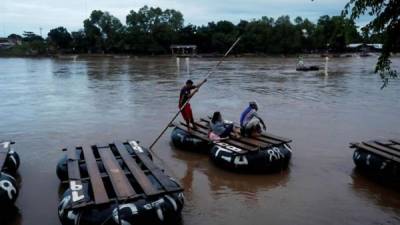 Balseros ayudan a migrantes hondureños a cruzar el río Suchíate que divide Guatemala y México hoy, viernes 19 de octubre de 2018, en Escuintla (Guatemala), para desde ahí continuar su viaje a Estados Unidos. EFE
