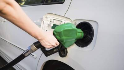 Female hand holding green pump filling gasoline