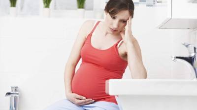 Pregnant Woman Suffering With Morning Sickness In Bathroom