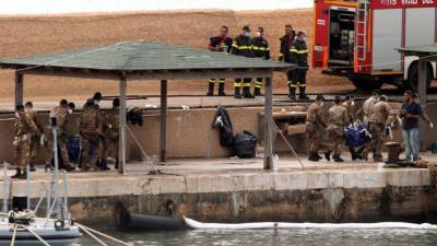 Varios militares italianos trasladan los cadáveres de víctimas del naufragio del barco de inmigrantes que tuvo lugar frente a la isla de Lampedusa, en el puerto de Lampedusa (Italia),