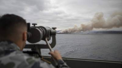 Un militar observa el humo de los incendios desde un barco de la Real Marina Australiana, cerca de la ciudad de Eden, en estado de Nueva Gales del Sur.