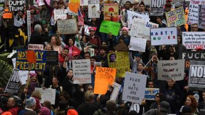 Protesters carry anti-Trump signs during a 'Not My President Day' demonstration outside City Hall in Los Angeles, California, on February 20, 2017. / AFP PHOTO / Mark RALSTON
