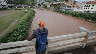 Un hondureño observa desde un puente la crecida de un río | Archivo