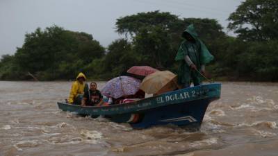 Personas se trasladan en una lancha sobre el río Goscorán, cuyo cauce ha crecido debido a las lluvias dejadas por la tormenta tropical Pilar, en la zona sur de Honduras.