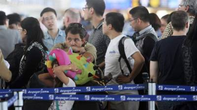 Viajeros esperan en la terminal del aeropuerto de Santiago. La huelga se suspende en momentos en los que las filas comenzaban a hacerse interminables.