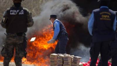 Un policía hondureño tira un fardo de cocaína a las llamas donde se destruyeron 1,426 kilos de droga incautada por las autoridades hondureñas en diferentes operaciones contra el narcotráfico el pasado mes de febrero.