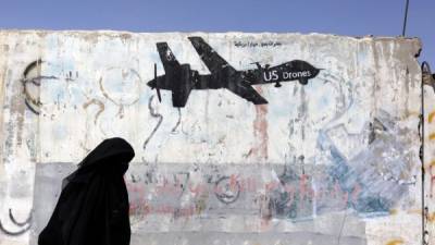 Una mujer camina junto a una pintada en un mural que representa un avión no tripulado o dron estadounidense en Saná (Yemen) hoy, 17 de octubre de 2017. EFE