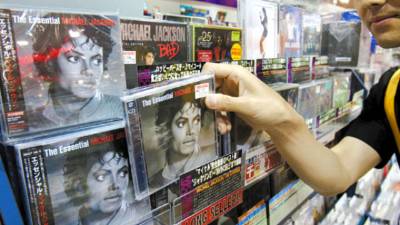 FILE - In this June 26, 2009 file photo, Ryosuke Kawada, an employee of Tower Records, shows a Michael Jackson CD in Tokyo. (AP Photo/Koji Sasahara, file)