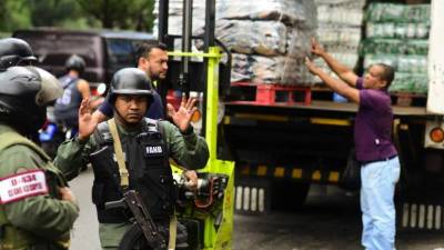 Los miembros de la Policía Nacional venezolana custodian un supermercado en el que descargan alimentos. Fotos: AFP/Ronaldo Schemidt