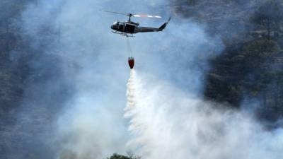 A Honduran air force helicopter drops water on a forest fire on the outskirts of Tegucigalpa on February 14, 2019. - The Honduran Fire Department reported that thousands of acres of forest have caught fire in the last few hours in different parts of the country, including the Celaque Mountain National Park in western Honduras. (Photo by ORLANDO SIERRA / AFP)