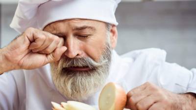 Master chef cutting onion with tears in his eyes
