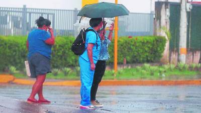 Pobladores cruzan una avenida en una zona del norte de Honduras, entre la lluvia.