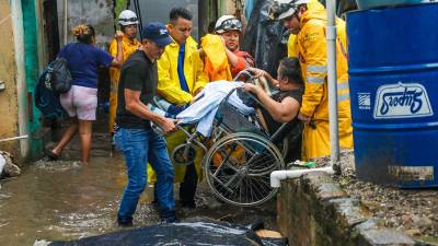 Personal de Protección Civil de El Salvador ayuda a evacuar a personas en zonas de riesgo por inundaciones.