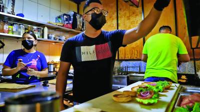 Jóvenes preparan hamburguesas en su pequeño negocio en El Centro. Foto: Melvin Cubas.