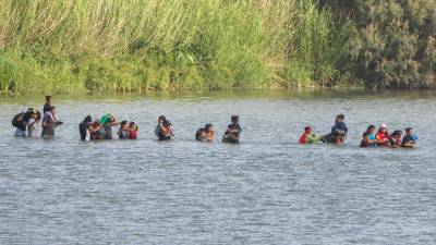 Un grupo de migrantes cruza el río Bravo pese al despliegue de seguridad de las autoridades texanas para impedir su paso.