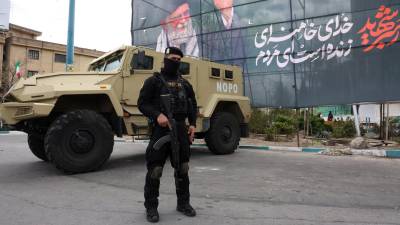 Un miembro de las fuerzas de seguridad iraníes monta guardia junto a una pancarta en honor al exlíder supremo iraní Ali Jamenei, en Teherán.