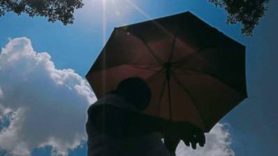 Hondureña se cubre del sol con una sombrilla | Fotografía de archivo
