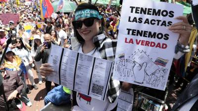 Una ciudadana venezolana sostiene carteles en una concentración para manifestarse en contra de los resultados oficiales de las elecciones en Venezuela.
