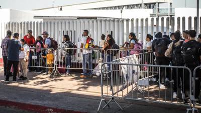 Fotografía de archivo en donde migrantes hacen fila en la garita el Chaparral para cruzar la frontera hacia Estados Unidos, en la ciudad de Tijuana, en Baja California (México).