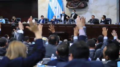 Diputados de Honduras levantan su mano para votar en sesión del Congreso Nacional.