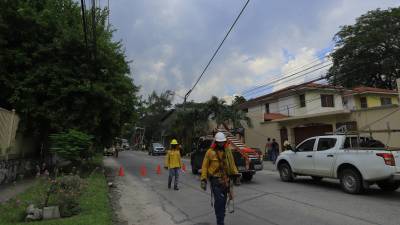 Cuadrillas de la ahora desaparecida EEH, dando respuesta sobre un poste del tendido eléctrico que cayó sobre varios carros en la colonia Stibys de San Pedro Sula .
