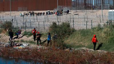 Migrantes permanecen cerca del muro que separa la frontera estadounidense en la Ciudad Juárez, Chihuahua (México).