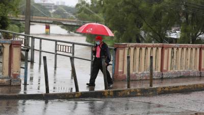 Un ciudadano camina mientras al fondo se ve el elevado nivel del río Choluteca, en Tegucigalpa (Honduras).