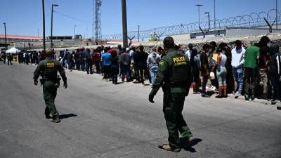 Cientos de migrantes esperan en un puerto de entrada a EEUU para entregarse a la Patrulla Fronteriza.