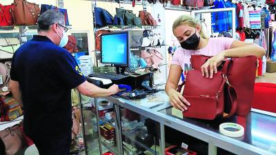 Un microempresario vende una cartera a una cliente en su tienda de ropa y accesorios.