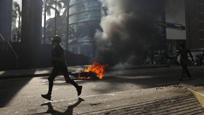Un manifestante corre durante enfrentamientos entre opositores y miembros de la Guardia Nacional Bolivariana (GNB), por los resultados de las elecciones presidenciales este lunes, en Caracas (Venezuela). EFE/ Henry Chirinos