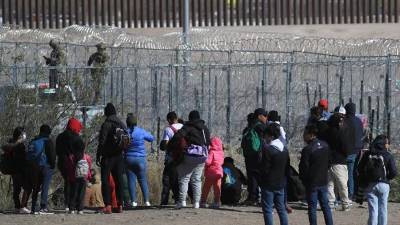 Un grupo de migrantes frente al muro en la frontera de EEUU y México.