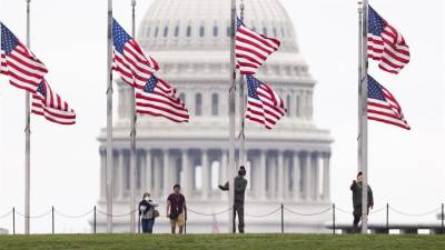 Funcionarios de Parques Nacionales ondean las banderas a media asta, este 12 de mayo de 2022 en Washington, para recordar a los fallecidos por covid-19, que superan el millón de personas en el país.