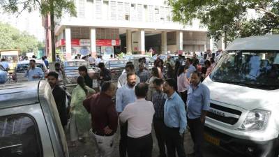 Ciudadanos permanecen fuera de sus oficinas después de que se sintieran temblores en Nueva Delhi, India.