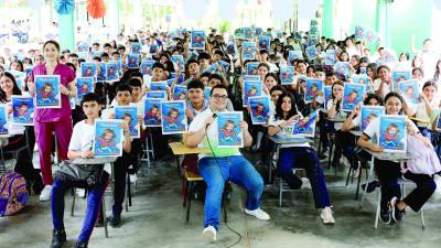 <b>Josías Guzmán y Claudia Avilés sonríen junto a estudiantes del colegio José Castro López con el fascículo número siete de Mente Santa.</b>