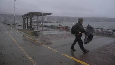 Un hombre camina frente a la costa durante un clima lluvioso.