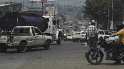 Automóviles transitan por una avenida en medio de una densa capa de humo causada por un incendio este martes, en la ciudad de Tegucigalpa.