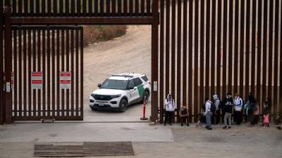 Un grupo de migrantes esperan poder entregarse a la Patrulla Fronteriza estadounidense en la frontera entre Tijuana y California.