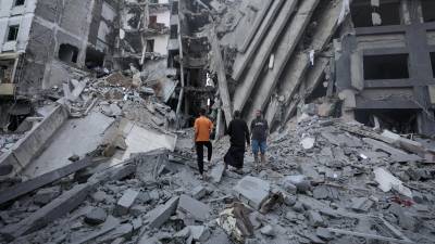 Paletinianos inspeccionan los daños en los alrededores del edificio destruido del Banco Nacional tras los ataques aéreos israelíes, en la ciudad de Gaza.
