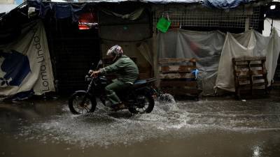Un motociclista transita por una calle inundada en el centro de San Salvador, en una fotografía de archivo.