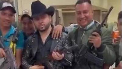 El cantante Larry Hernández (centro, con sombrero negro) desató polémica por posar con armas.