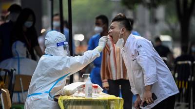 A health worker takes a swab sample from a man to be tested for the Covid-19 coronavirus at a makeshift testing site outside a shopping mall in Beijing on June 15, 2022. (Photo by Jade GAO / AFP)