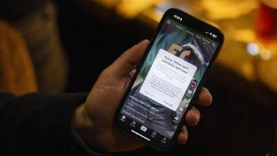 Una persona sostiene un teléfono inteligente con un mensaje en su aplicación de TikTok indicando que no está disponible en Washington, DC.