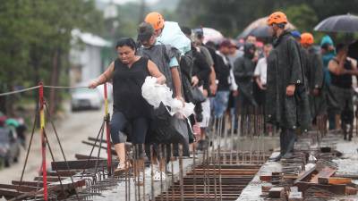 Personas evacuan debido a las crecidas de ríos y quebradas por el paso de la tormenta Sara, el sábado, en el norte de Honduras.