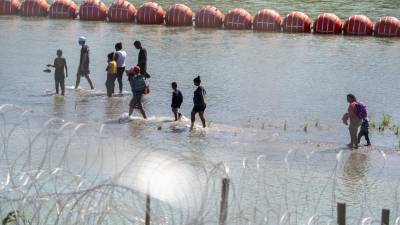 Un grupo de migrantes cruza el Río Bravo pese a la barrera de boyas instaladas por el Gobierno de Abbott.